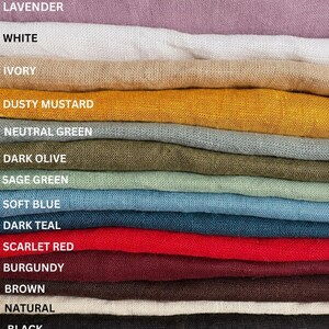 K&ouml;nnte beinhalten: Ein Stapel gefalteter Stoffe in verschiedenen Farben, beschriftet mit: Lavender, White, Ivory, Dusty Mustard, Neutral Green, Dark Olive, Sage Green, Soft Blue, Dark Teal, Scarlet Red, Burgundy, Brown, Natural und Black.