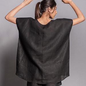 May include: A black linen top with a loose, flowing fit and a scoop neckline. The top is made of a lightweight, breathable fabric and has a relaxed, casual style.