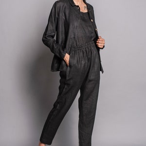 May include: A black long-sleeved button-down jacket, a matching black sleeveless top, and black trousers with an elasticized waistband and side pockets. The ensemble is paired with beige ankle boots featuring a side buckle and a block heel.