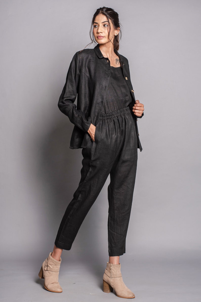 May include: A black long-sleeved button-down jacket, a matching black sleeveless top, and black trousers with an elasticized waistband and side pockets. The ensemble is paired with beige ankle boots featuring a side buckle and a block heel.