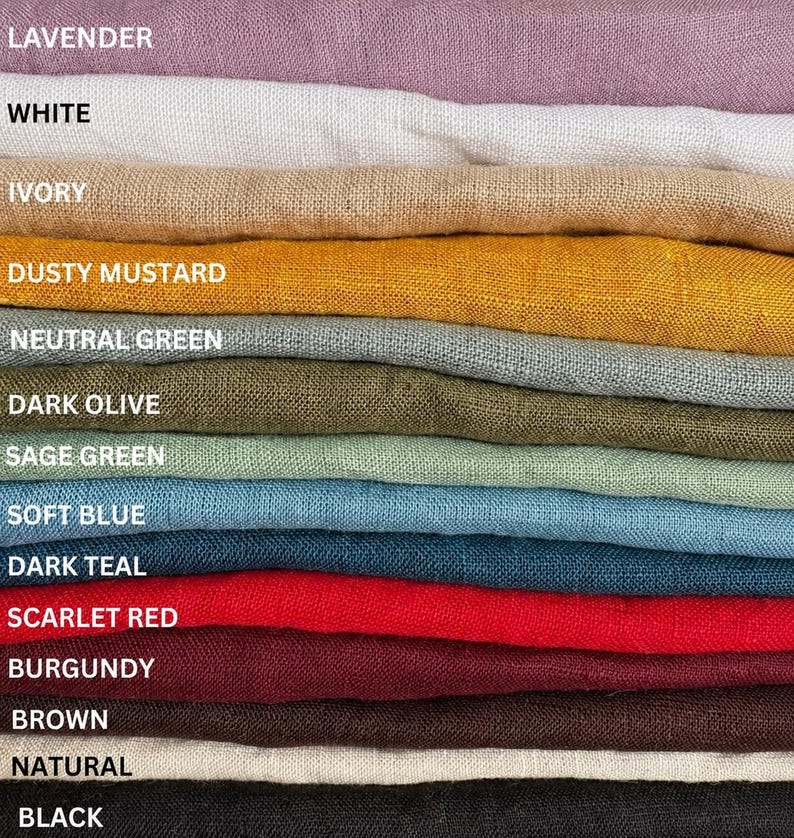 May include: A stack of folded fabric swatches in various colors labeled as lavender, white, ivory, dusty mustard, neutral green, dark olive, sage green, soft blue, dark teal, scarlet red, burgundy, brown, natural, and black.