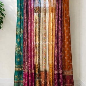 Op de afbeelding: Een set kleurrijke, bedrukte gordijnen in tinten van teal, fuchsia, crème, oranje en roest. De gordijnen hangen aan een donkerbruine stang en hebben ingewikkelde bloemen- en geometrische ontwerpen. De tekst "Fashion Point" is zichtbaar.