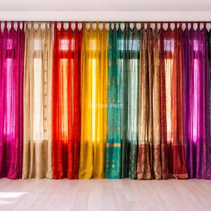 Op de afbeelding: Een levendige weergave van kleurrijke gordijnen in tinten blauw, roze, goud, rood, geel, groen en paars. De gordijnen hangen aan een stang en creëren een regenboogeffect, wat een decoratieve touch aan de kamer geeft. De gordijnen zijn gemaakt van een transparante stof.