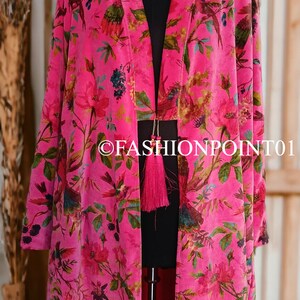 Puede incluir: Un kimono de terciopelo rosa con estampado floral y de p&aacute;jaros. El kimono tiene un cierre de borla y se muestra en un maniqu&iacute;.