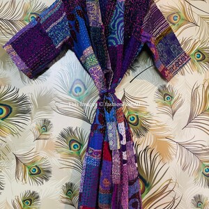 Op de afbeelding: Een badjas met lange mouwen en een patchworkontwerp in verschillende tinten paars, blauw en roze. Het kledingstuk is voorzien van ingewikkelde kantha-stiksels en een bijpassende ceintuur. De tekst "This Images &copy; fashion786m01" is zichtbaar.