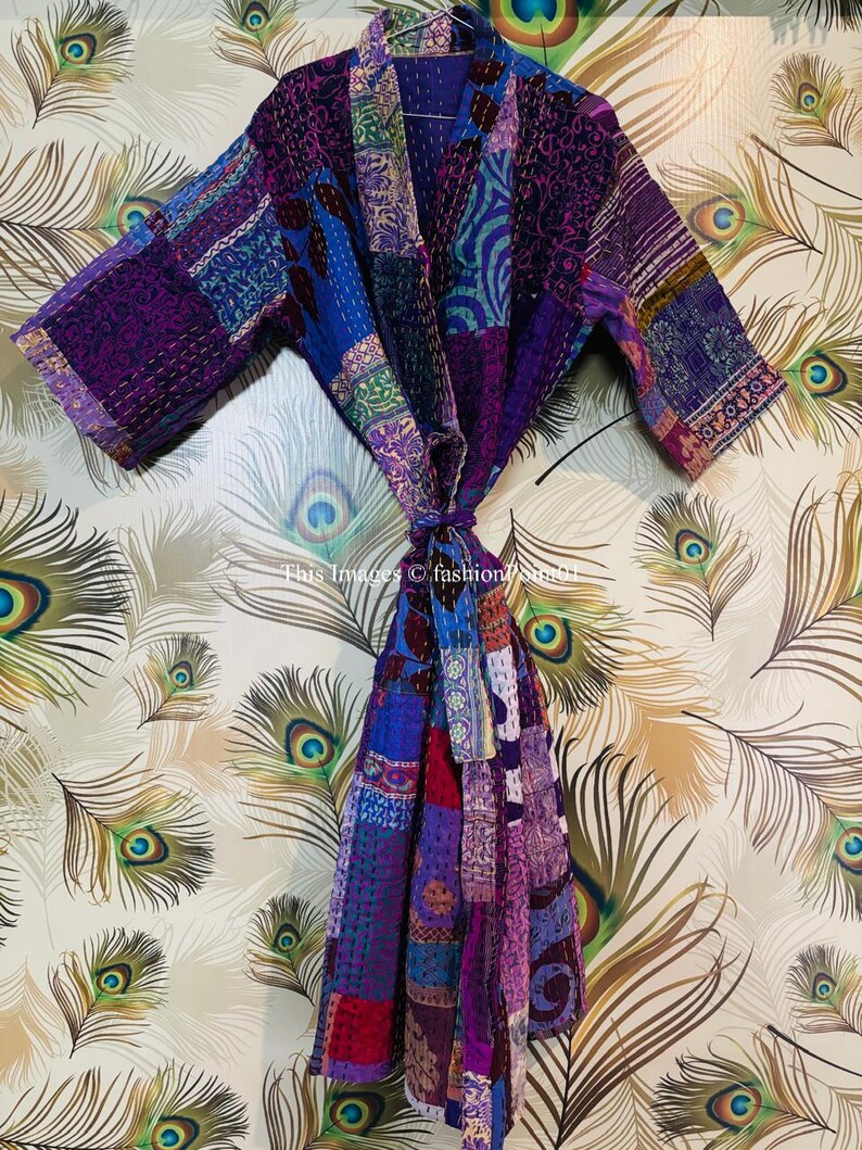 Op de afbeelding: Een badjas met lange mouwen en een patchworkontwerp in verschillende tinten paars, blauw en roze. Het kledingstuk is voorzien van ingewikkelde kantha-stiksels en een bijpassende ceintuur. De tekst "This Images &copy; fashion786m01" is zichtbaar.