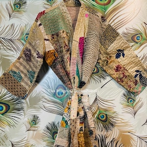 Puede incluir: Una bata kimono de patchwork con una variedad de colores y patrones, incluyendo marrón, verde, rosa y azul. La bata está atada a la cintura con una faja.