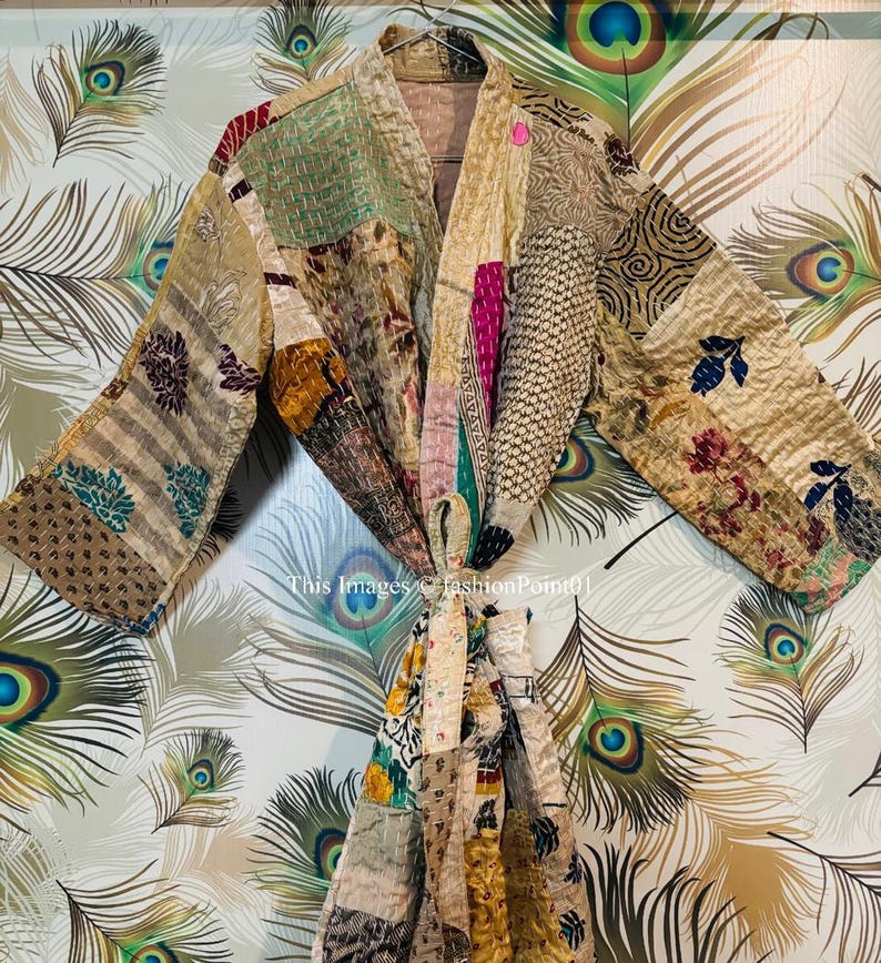 Puede incluir: Una bata kimono de patchwork con una variedad de colores y patrones, incluyendo marr&oacute;n, verde, rosa y azul. La bata est&aacute; atada a la cintura con una faja.