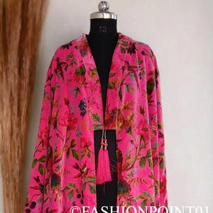 Puede incluir: Un kimono largo de terciopelo rosa con estampado floral con p&aacute;jaros y flores. El kimono tiene un lazo de borla en la cintura.