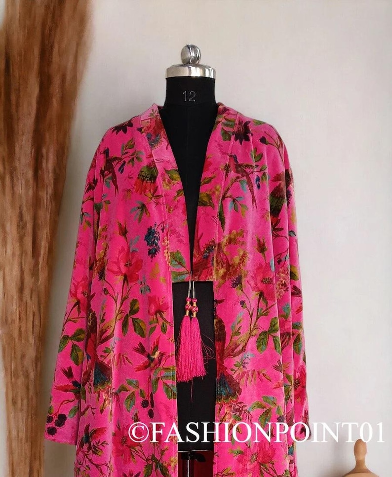 Puede incluir: Un kimono largo de terciopelo rosa con estampado floral con p&aacute;jaros y flores. El kimono tiene un lazo de borla en la cintura.