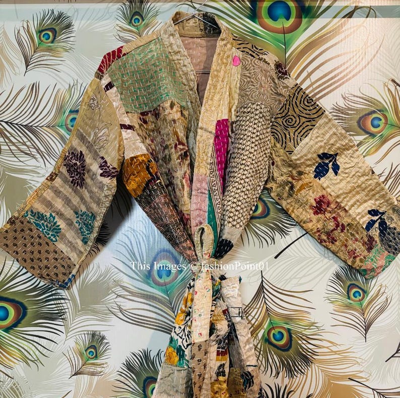 Puede incluir: Una bata kimono de patchwork con una variedad de colores y patrones, incluyendo dorado, marr&oacute;n, rosa y verde. La bata est&aacute; atada a la cintura con una faja.