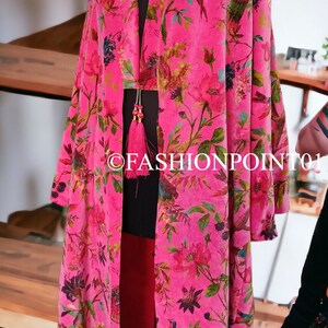 Puede incluir: Un kimono de terciopelo rosa con estampado floral que presenta p&aacute;jaros y flores. El kimono tiene una silueta larga y fluida y un detalle de borla en el escote.