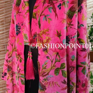 Puede incluir: Un kimono de terciopelo rosa con estampado floral y de p&aacute;jaros. El kimono tiene cuello en V y mangas largas. Tiene una borla dorada en la parte delantera.