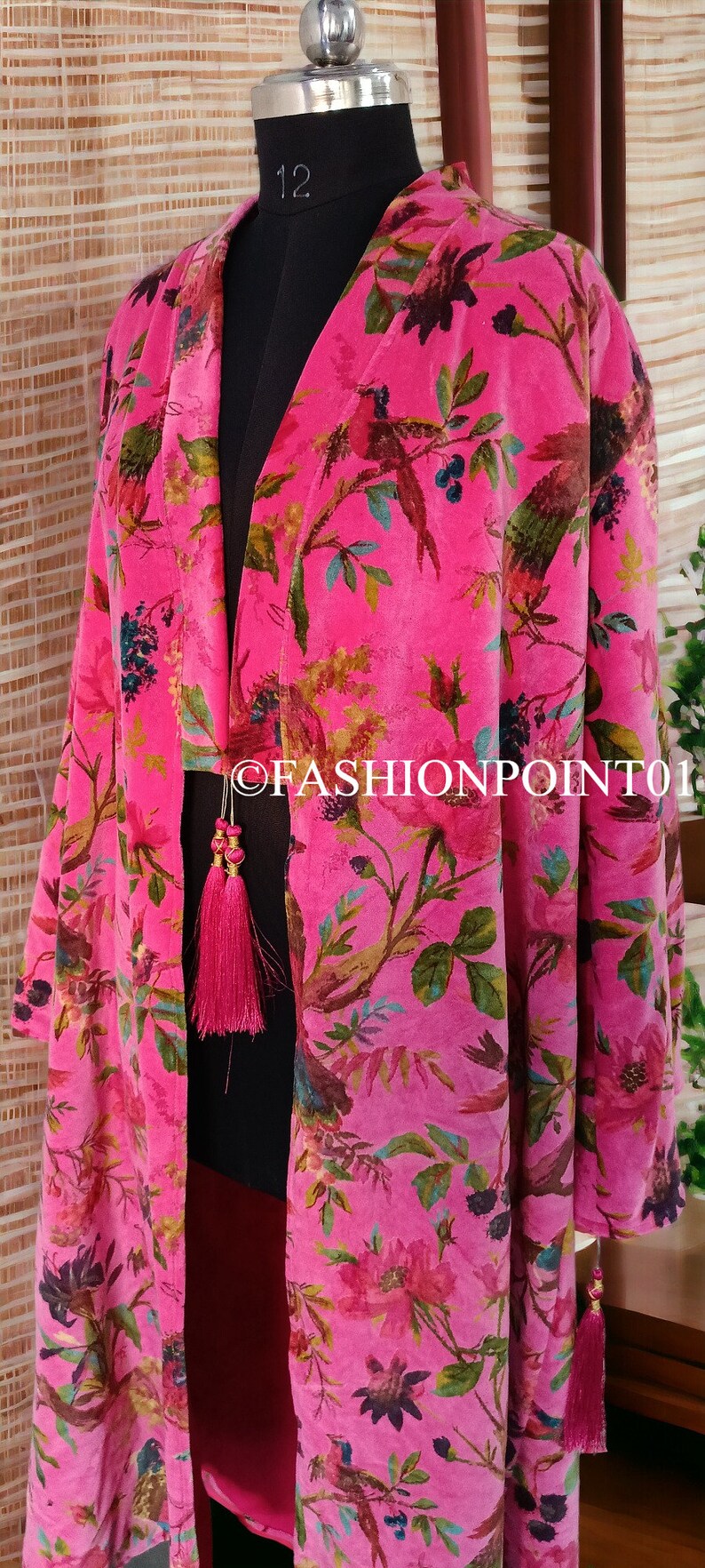 Puede incluir: Un kimono de terciopelo rosa con estampado floral y de p&aacute;jaros. El kimono tiene cuello en V y mangas largas. Tiene una borla dorada en la parte delantera.