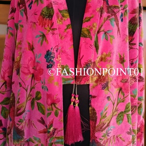 Puede incluir: Un kimono de terciopelo rosa con estampado floral y de p&aacute;jaros. El kimono tiene una abertura larga y abierta en la parte delantera y un cierre de lazo en la cintura. El kimono est&aacute; decorado con dos borlas rosas.