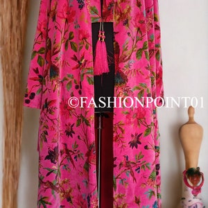 Puede incluir: Un kimono de terciopelo rosa con estampado floral y de p&aacute;jaros. El kimono tiene un detalle de borla en la parte delantera.