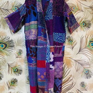 Op de afbeelding: Een kamerjas met lange mouwen en een patchworkontwerp in diverse tinten paars, blauw en rood, geaccentueerd door ingewikkelde witte kantha-stiksels. Het kledingstuk toont de tekst This Images &copy; fashionPoint01 aan de voorzijde.