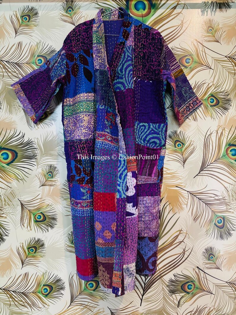 Op de afbeelding: Een kamerjas met lange mouwen en een patchworkontwerp in diverse tinten paars, blauw en rood, geaccentueerd door ingewikkelde witte kantha-stiksels. Het kledingstuk toont de tekst This Images &copy; fashionPoint01 aan de voorzijde.