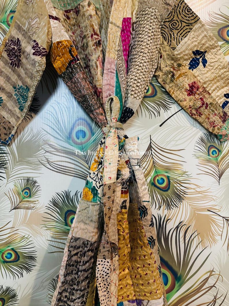 Puede incluir: Una bata de patchwork con una variedad de colores y patrones, incluyendo dise&ntilde;os florales, geom&eacute;tricos y paisley. La bata est&aacute; atada a la cintura y tiene mangas largas.