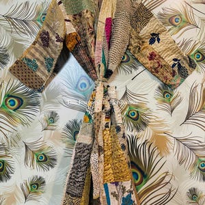 Puede incluir: Una bata kimono de patchwork con una variedad de colores y patrones, incluyendo marr&oacute;n, dorado, azul y verde. La bata est&aacute; hecha de seda y tiene un cierre de lazo.
