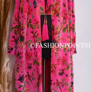 Puede incluir: Un kimono largo de terciopelo rosa con estampado floral y de p&aacute;jaros. El kimono tiene un cuello en V profundo y un cierre de lazo en la cintura. El kimono est&aacute; decorado con una borla rosa.