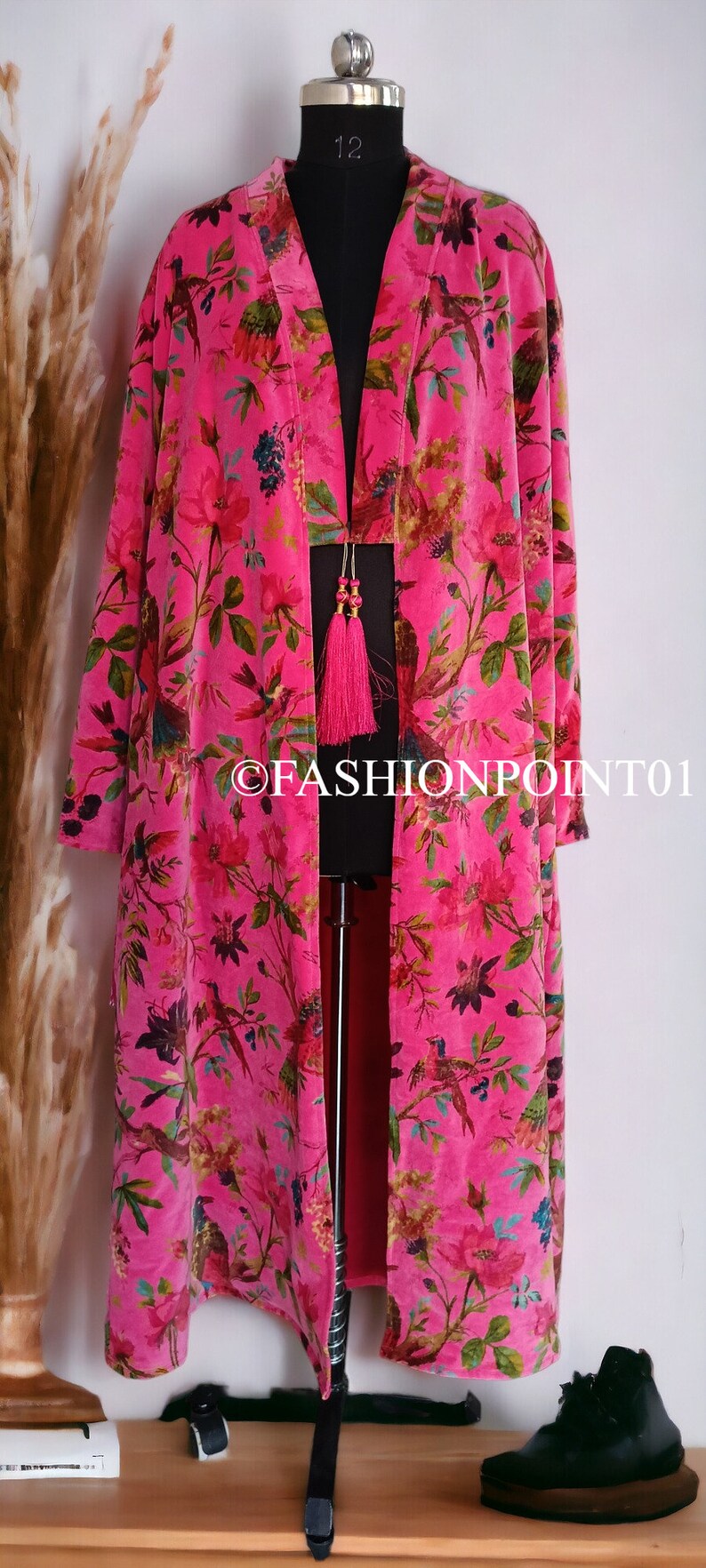 Puede incluir: Un kimono largo de terciopelo rosa con estampado floral y de p&aacute;jaros. El kimono tiene un cuello en V profundo y un cierre de lazo en la cintura. El kimono est&aacute; decorado con una borla rosa.