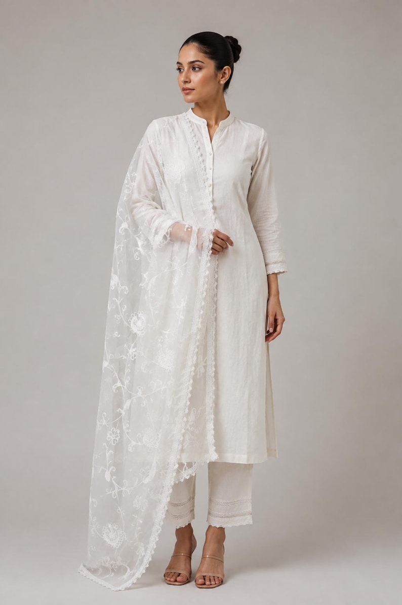 Pu&ograve; includere: Un completo bianco a tre pezzi composto da una tunica a maniche lunghe con colletto alla coreana e abbottonatura frontale, pantaloni dritti abbinati con bordo in pizzo sull'orlo e una dupatta bianca trasparente con ricami floreali.