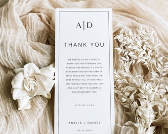 May include: A white thank you card with black text. The card says "AD" in a minimalist font at the top and "Thank You" in a larger font below. The text continues with a message of gratitude for attending the wedding and a note about celebrating the future together. The card is signed "Amelia + Daniel" and includes the date "03.03.2023".
