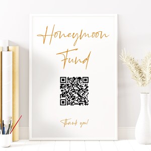 Könnte beinhalten: Weißer Rahmen mit einer goldenen Aufschrift, die "Honeymoon Fund" lautet, und einem schwarz-weißen QR-Code. Der Text "Vielen Dank!" ist ebenfalls in Gold geschrieben.