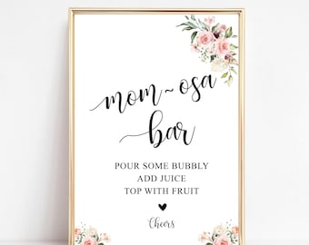 May include: A printable sign for a "Mom-osa Bar" with pink floral accents. The sign instructs guests to "Pour some bubbly, add juice, top with fruit". It also includes the text "Cheers" with a heart.