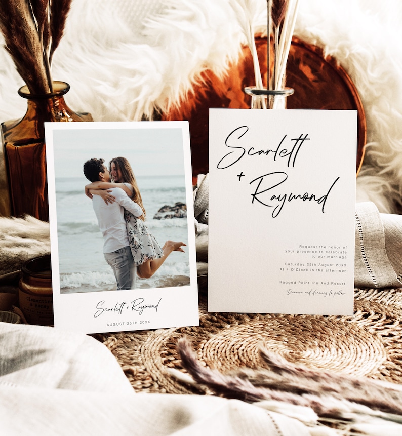May include: Wedding invitation featuring a photograph of a couple embracing on a beach. The invitation is white with black text and reads "Scarlett + Raymond" and "August 25th 20XX".