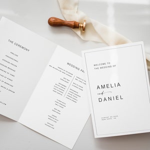 May include: A white wedding program with black text. The front cover reads "Welcome to the Wedding of Amelia and Daniel" with the date and location below. The inside pages list the order of the ceremony and the wedding party.