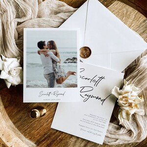 May include: A wedding invitation featuring a photograph of a couple on a beach. The invitation is white with black text and reads "Scarlett & Raymond" and "August 25th 20XX". The invitation also includes the text "Request the honour of your presence to celebrate our marriage" and "Saturday 25th August 20XX at 4 O'Clock in the afternoon" and "Ragged Point Inn And Resort".