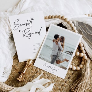 May include: Wedding invitation featuring a photograph of a couple embracing on a beach. The invitation is white with black text and reads "Scarlett + Raymond" and "August 25th 20XX".