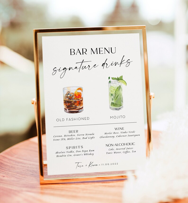 May include: A white sign with a gold frame, listing a bar menu with signature drinks. The menu includes an old fashioned, mojito, beer, wine, spirits, and non-alcoholic options. The sign also includes the text "Tara & Kevin 11.09.2022".