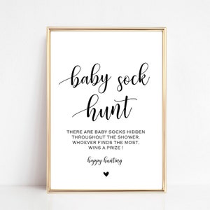 May include: A white sign with black text that reads "baby sock hunt" and "THERE ARE BABY SOCKS HIDDEN THROUGHOUT THE SHOWER. WHOEVER FINDS THE MOST. WINS A PRIZE! happy hunting".