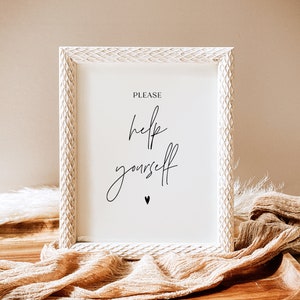 May include: A framed sign with the words "PLEASE help yourself" in elegant black script. The white frame has a textured, carved design. A small black heart is below the text. The sign rests on a wooden tray with a beige fabric.
