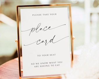 May include: A gold-framed sign with white background and black text that reads "PLEASE TAKE YOUR place card TO YOUR SEAT SO WE KNOW WHAT YOU ARE HAVING TO EAT".