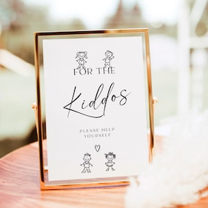 Op de afbeelding: Een gouden kader met de tekst "For the Kiddos" en stokpoppetjes van kinderen. Het bord zegt ook "Please help yourself" met een hartje.