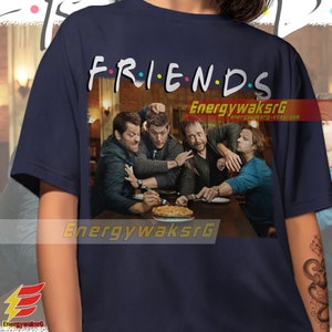 May include: A navy blue t-shirt with a graphic of four men sitting at a table with a pie. The text "FRIENDS" is above the graphic with colorful dots between the letters.