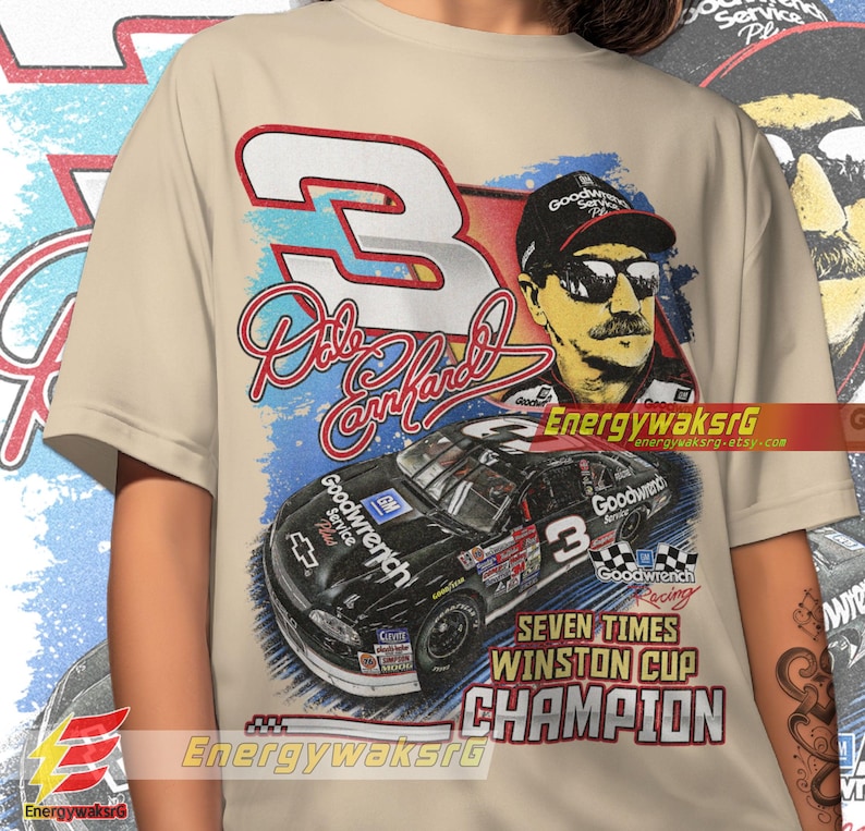 Pu&ograve; includere: Una t-shirt beige con una grafica in stile vintage di Dale Earnhardt, un pilota di auto da corsa, e la sua auto da corsa numero 3. La grafica include il testo "Goodwrench", "Seven Times Winston Cup Champion", e la firma di Dale Earnhardt.