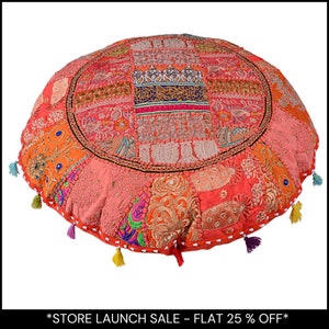 May include: Circular patchwork floor cushion in coral, orange, and pink hues. The cushion showcases diverse fabric patterns and textures, with decorative tassels along the edge. A decorative home accent.