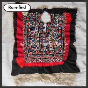 Puede incluir: Un fragmento textil vintage con intrincados bordados en una variedad de colores, incluyendo rojo, negro y blanco. La pieza presenta un panel central bordado con un diseño geométrico, enmarcado por tela roja y negra. El texto "Rare find" está en la esquina superior izquierda.