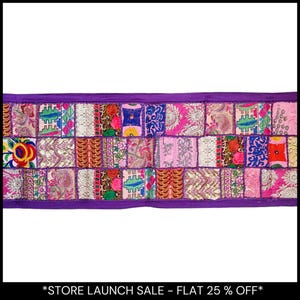 Puede incluir: Textil rectangular de patchwork con una vibrante mezcla de colores y patrones. El diseño presenta una serie de cuadrados en tonos rosas, morados, azules y dorados, cada uno con detalles bordados únicos. Los bordes están ribeteados con un borde morado liso.