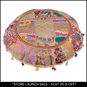 May include: Round, patchwork floor cushion with a variety of fabric patterns and colors, including beige, pink, red, and green. The cushion has a circular design with a decorative border and small tassels around the edge. The text "STORE LAUNCH SALE - FLAT 25% OFF" is at the bottom.