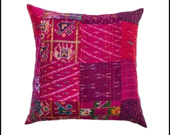May include: A square decorative pillow with a patchwork design in shades of pink, magenta, and purple. The pillow features various fabric patterns and gold stitching. The overall theme is bohemian and eclectic.