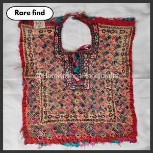 May include: A colourful, embroidered vintage textile with a central opening. The textile features a variety of colours, including red, pink, blue, and green, and is labelled "Rare find". The design incorporates floral and geometric patterns.