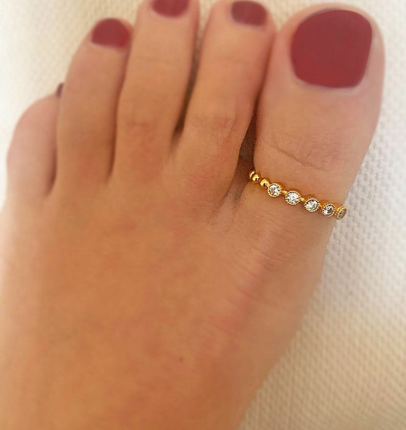May include: Gold toe ring with small clear stones set in a beaded band.