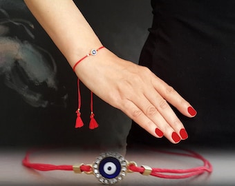 Può includere: Braccialetto di corda rossa con un ciondolo di occhio turco blu e perline d'argento. Il braccialetto ha nappe ad ogni estremità.