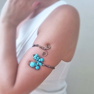 May include: A copper wire arm cuff with a turquoise stone design. The cuff is made of thin copper wire and has a simple, elegant design.
